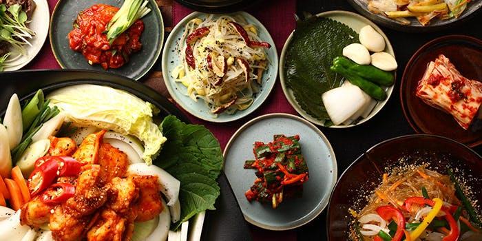 韓国料理のサムギョプサルと梅酒のロックグラスが並んだ食欲をそそる食卓の風景